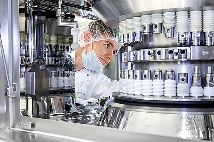 Junger Mann in Laborkleidung an einer Industrieanlage.