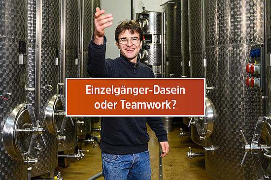 Text-Logo: Einzelgänger-Dasein oder Teamwork? Bild: Ein junger Mann steht in einem Keller vor Metalltanks. Er hebt die Hand, als wollte er andere Menschen hineinwinken. 