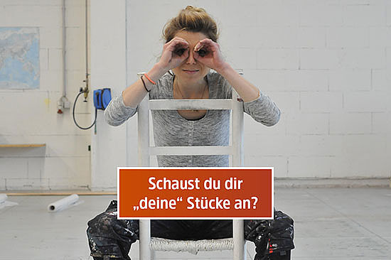 Textfeld mit Frage: „Schaust du dir `deine´ Stücke an?“ Amelie sitzt auf einem Stuhl; sie hält die Hände wie ein Fernglas an die Augen.