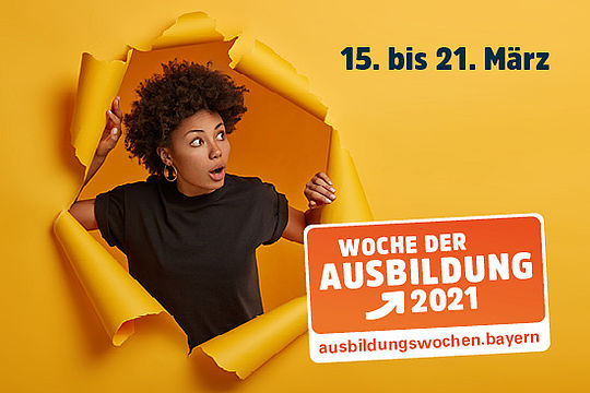 Eine junge Frau guckt erstaunt durch ein großes Loch in einer Papierwand.