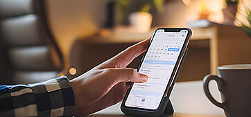 Ein Smartphone in der Hand auf dem ein Kalender geöffnet ist.