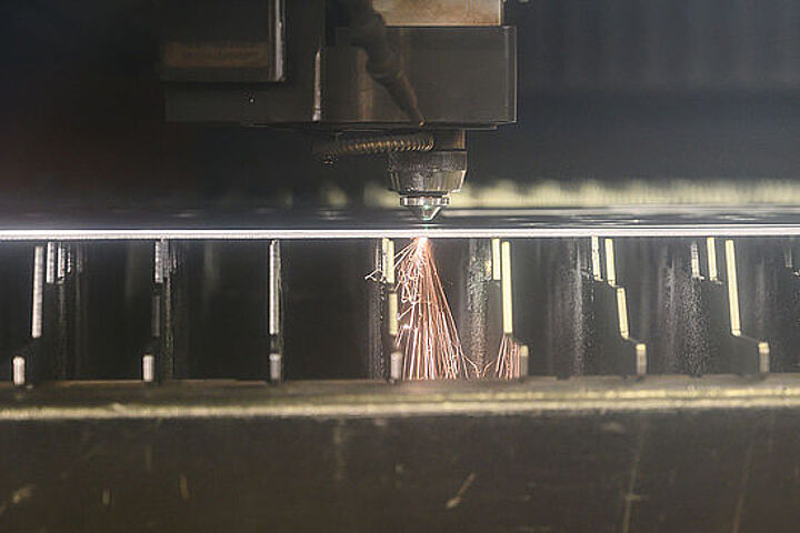 Detailaufnahme: ein Laser schneidet Formen aus einer Platte.