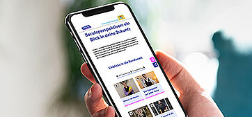 Ein Smartphone in der Hand, auf dem eine Internetseite zu sehen ist.