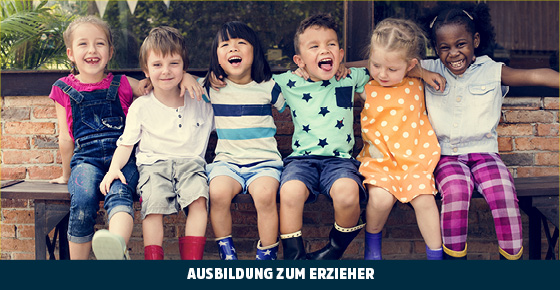 Sechs Kinder in Sommerkleidung und Gummistiefeln sitzen lachend und sich umarmend auf einer Holzbank 
