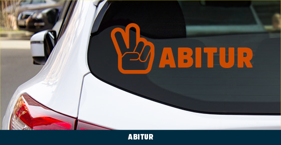 Ausschnitt einer Rückansicht eines silbernen Autos: Über der Scheibe eine Illustration von einer Hand mit V-Zeichen und dem Wort Abitur.