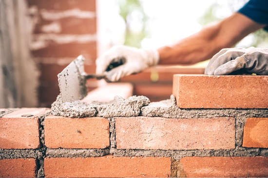 Nahaufnahme: Jemand baut eine Mauer aus Ziegelsteinen.