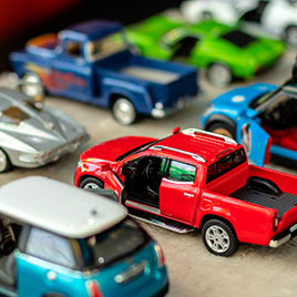 Spielzeugautos in verschiedenen Farben und Modellen stehen aufgereiht auf einem Tisch.